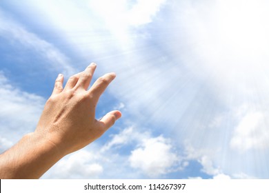 Adult hand reaching out towards the sky