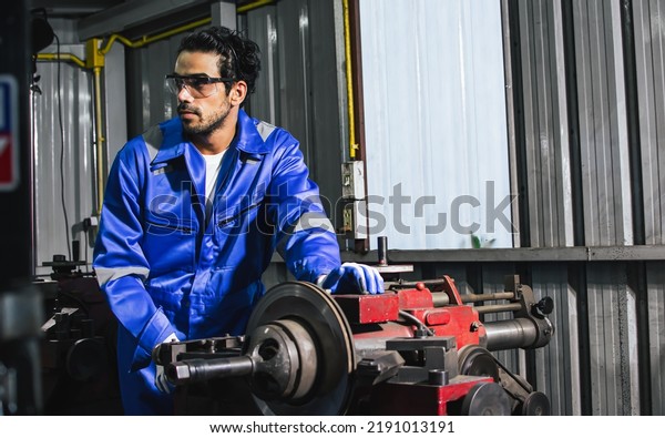 Adult handsome male mechanics wearing uniform,\
using machine for fix, repair car or automobile components,\
teamwork helping, working in car maintenance service center or\
shop. Industry Concept