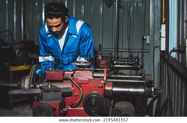 Adult handsome\
male mechanics wearing uniform, using machine for fix, repair car\
or automobile components,  working in car maintenance service\
center or shop. Industry\
Concept