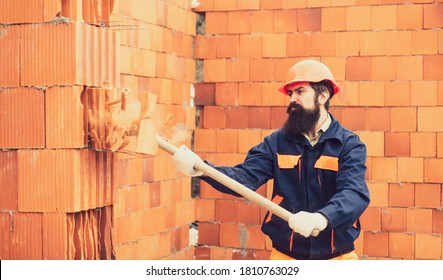 Adult Handsome Worker Builder Using Hammer And Smash Tool At Construction Site. Man Using Sledge-hammer. Labor Are Using Hammer Smash Destroy Cement Wall