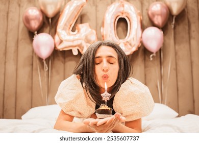 Adult happy beautiful woman forty years with festive cupcake with candle in hands, isolated on white, birthday girl. Natural looking mature woman celebrate happy birthday blow one cupcake candle - Powered by Shutterstock