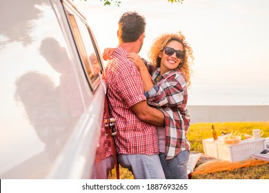 Adult happy couple enjoy love and relationship during outdoor leisure activity together - concept of travel with van and summer holiday vacation for cheerful people - beautiful woman man husband hug