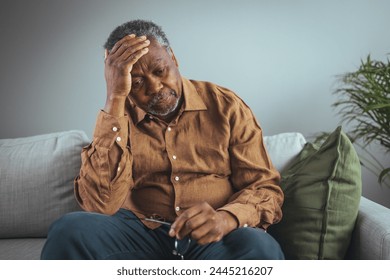 An adult has a headache. He sits and holds his hands on his head in a dark room. Concept of dramatic loneliness, sadness, depression, sad emotions, disappointment, nursing, pain. - Powered by Shutterstock