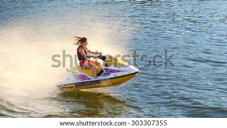 Adult having fun jumping a wave riding yellow and white jet ski in California Ocean