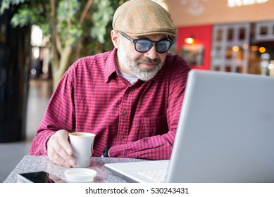 Adult Hipster man using computer in public place 