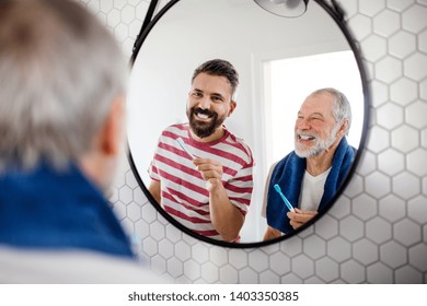 An Adult Hipster Son And Senior Father In Bathroom Indoors At Home, Brushing Teeth.