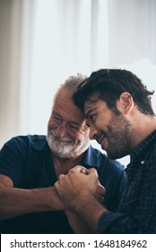 An Adult Hipster Son And Senior Father At Home, Talking.