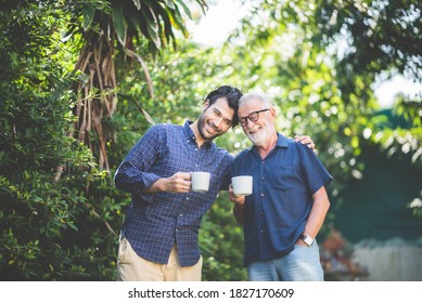 An adult hipster son and senior father drinking coffee in the garden at home, happy talking in the morning - Powered by Shutterstock