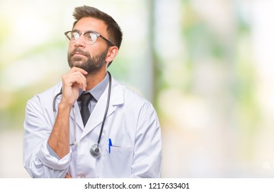 Adult hispanic doctor man over isolated background with hand on chin thinking about question, pensive expression. Smiling with thoughtful face. Doubt concept. - Powered by Shutterstock