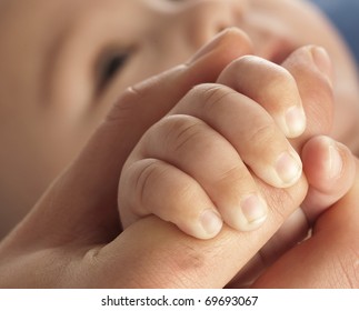 adult holding a baby hand, extreme closeup photo
