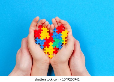 Adult And Kid Hands Holding Colorful Heart On Blue Background. World Autism Awareness Day Concept