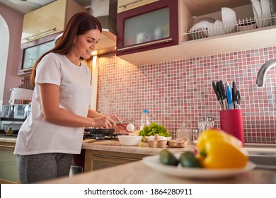 Adult lady alone in the kitchen smashing the egg with the help of a small knife - Powered by Shutterstock