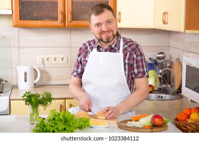 Adult Male 40 Years Old Makes A Sandwich With Cheese And Green Lettuce Leaves. Man Is Cooking At Home In The Kitchen. Vegetarian Menu In The Diet - Taking Care Of Health And Longevity.