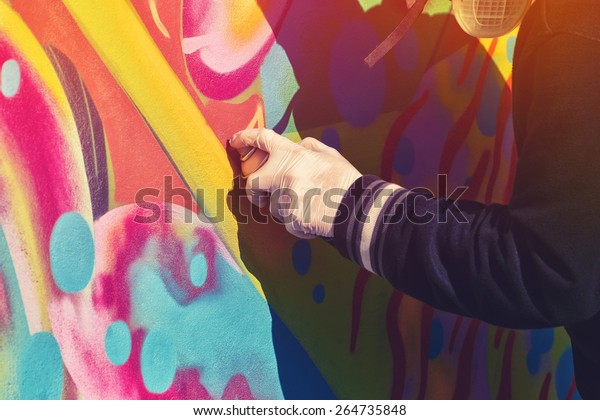 Adult Male
Graffiti Artist Paint Spraying the Wall, Urban Outdoors Street Art
Concept, Toned Image with Selective
Focus