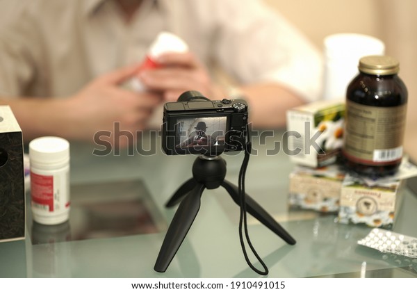 An adult male leads a video blog about alternative\
medicine. In his hands, he holds a jar of herbal medicines .\
Selective focus.