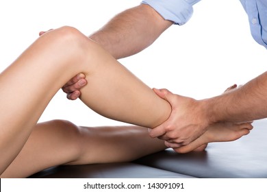 Adult male physiotherapist treating the foot of a female patient. Patient is sitting on a bed.