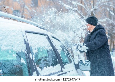 Adult Male Removing Snow From Car Roof With Brush In Winter Season