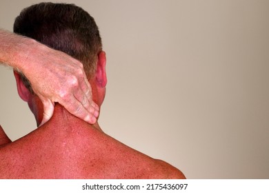 Adult male rubbing the back side of his neck with his hand as seen from a rear view close-up. Adult mature male 50 - 59 years massaging the back of his neck to help relive stress and tension
