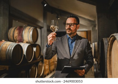 Adult man caucasian winemaker stand between barrels check wine quality hold clipboard - Powered by Shutterstock