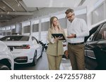 Adult man customer male buyer client wearing shirt consult with salesman signs documents choose auto want to buy new automobile in car showroom vehicle salon dealership store motor show. Sales concept