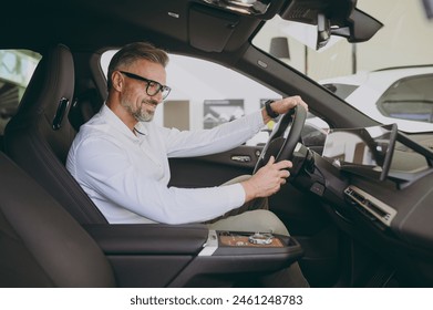 Adult man customer male buyer client wears shirt sit drive electric car hold steering wheel choose auto want to buy new automobile in showroom vehicle salon dealership store motor show. Sales concept - Powered by Shutterstock