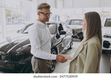 Adult man customer male buyer client wears shirt consulting with salesman shake hands choose auto want to buy new automobile in car showroom vehicle salon dealership store motor show. Sales concept - Powered by Shutterstock