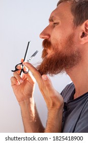 Adult Man Cutting His Own Beard And Mustache With Scissors And Comb. Caucasian Red Bearded Male Trimming Hair On Face At Home. Do It Yourself Self-made Haircut.Selfcare DIY During Quarantine Isolation