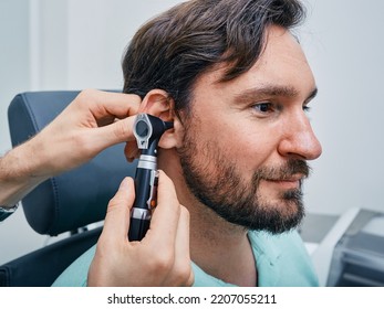 Adult Man During Ear Exam At Hearing Clinic. Audiologist Examining Male Patient Ear Using Otoscope, Close-up