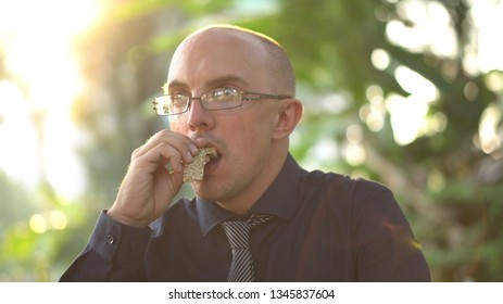 Adult Man Eating Healthy Organic Granola Bar In Park