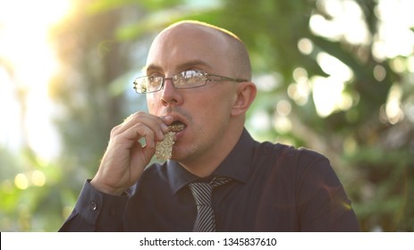 Adult Man Eating Healthy Organic Granola Bar In Park