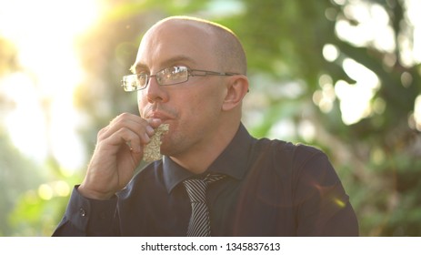 Adult Man Eating Healthy Organic Granola Bar In Park