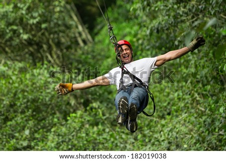 An adult man enjoying an adrenaline-filled ziplining adventure through the lush forests of Ecuador, soaring along a thrilling zip line.