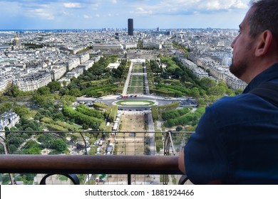 Adult man enjoying the beautiful views of the fields of Mars from the second floor of the Eiffel Tower in Paris