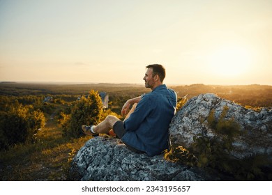 Adult man enjoying sunset sitting on top of the mountain  - Powered by Shutterstock