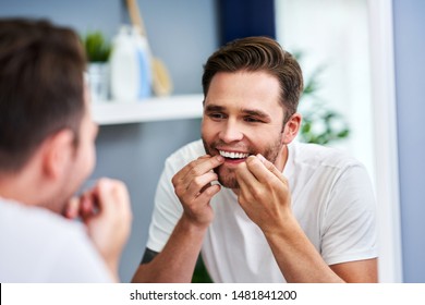 Adult Man Flossing Teeth In The Bathroom