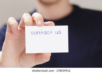 Adult Man Hand  Holding Card Contact Us In Front Of Camera, Blurred Background