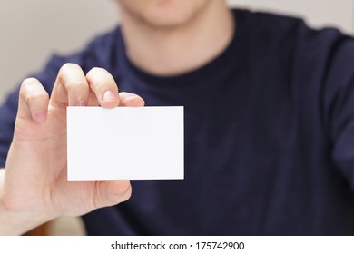 Adult Man Hand Holding Empty Business Card In Front Of Camera, Blurred Background