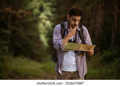 Adult man is hiking in forest. He is looking at map. - Powered by Shutterstock