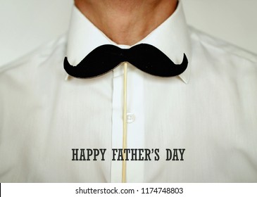 An Adult Man Holding A Fake Felt Moustache In A Stick In Front Of His White Shirt Like A Tie, Happy Father Day And Men Health Concept