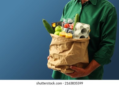 Adult Man Holding Paper Grocery Bag Filled With Daily Grocery From Super Market, Isolated On Blue Background, Copy Space. 