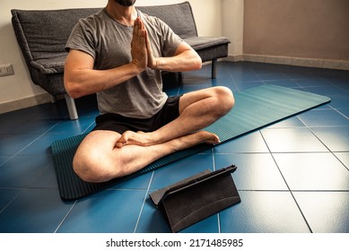 Adult Man At Home In The Yoga Position Of The Liberation Seen On A Tablet. Quarantine Training At Home. Fitness, Meditation And Healthy Lifestyle Concept.