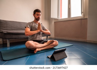 
Adult Man At Home In The Yoga Position Of The Liberation Seen On A Tablet. Quarantine Training At Home, Fitness, Meditation And Healthy Lifestyle Concept.