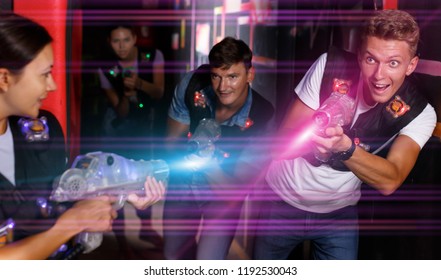 Adult man with laser guns  took aim and having fun with friends during laser tag game