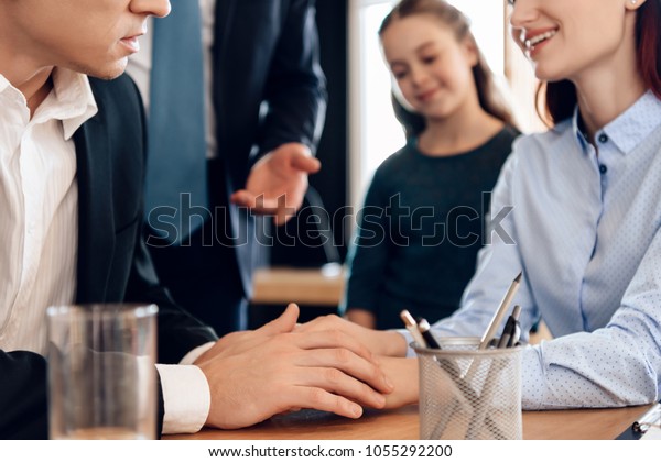 Adult\
man looks at wedding ring while sitting in divorce lawyer\'s office.\
Family in office of family lawyer. Young man and beautiful woman\
decide who will be main guardian of little\
girl.