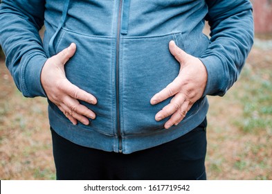 Adult Man With Overweight Holding Hands On Stomach And Frowning From Pain And Discomfort.Fat Man Suffer From Bally Indigestion.Body Part Cut Out