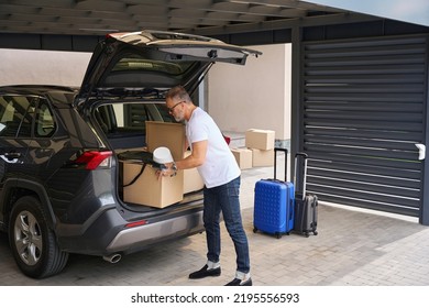 Adult man puts boxes of things in trunk of car. - Shutterstock ID 2195556593