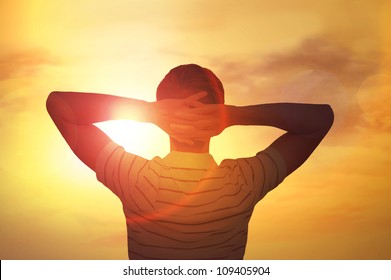 Adult man satisfied with nature beauty of sunset. Photo from behind against the sun - Powered by Shutterstock