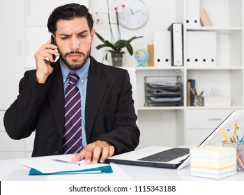 Adult Man Is Serious Talking Phone In His Work Place.