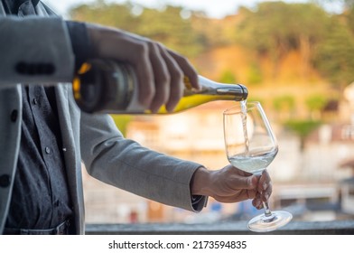 Adult man serving white wine on rooftop bar - Shutterstock ID 2173594835