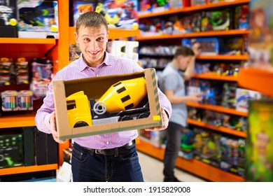 Adult Man Shopping In Store Of Kids Toys, Looking For Big Toy Car